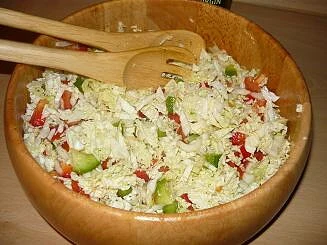 Chinese cabbage salad in wooden bowl with serving utensils