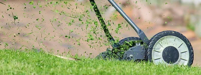 Traktor seka trávu na anglickém trávníku.