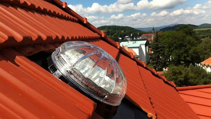 Moderní světlík nainstalovaný v červené taškové střechě domu.