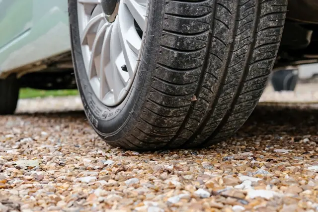 Automobilová pneumatika na štěrkové příjezdové cestě.