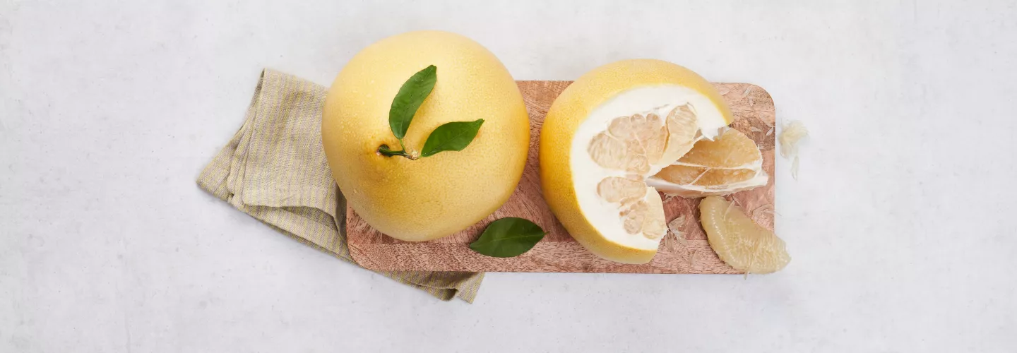 Celý žlutý pomerančový citrus s listy položený na dřevěném prkénku.
