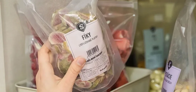 Ruce drží sáček se sušenými jablky mrazem v obchodě.