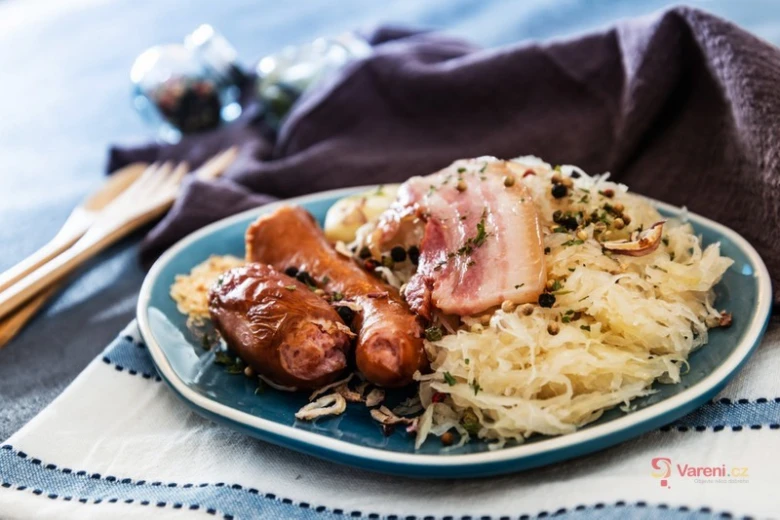 Kysané zelí podávané s klobásou a slaninou na talíři.