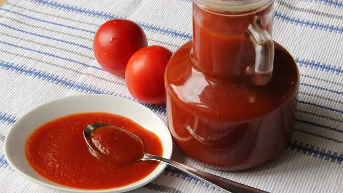 Domácí kečup z čerstvých rajčat v džbánu s lžící.