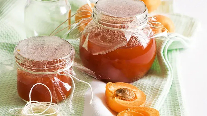 Doma vyrobená meruňková marmeláda v skleničkách s čerstvými meruňkami.