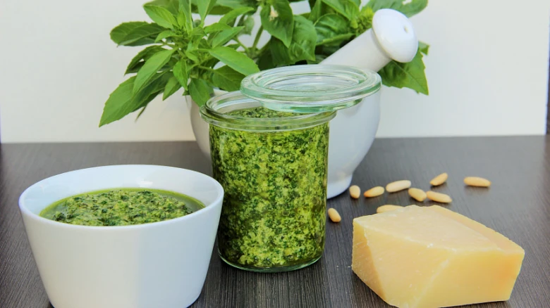 Bazalkové pesto v misce s ingrediencemi jako parmezán a piniové oříšky.