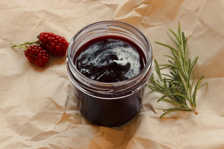 Sklenice ostružinové marmelády s čerstvými bobulí a rozmarýnem.