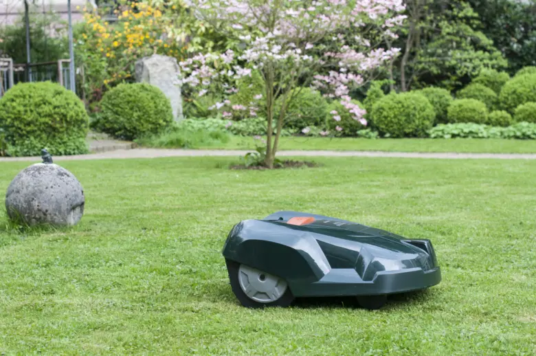 Robotická sekačka na trávu pracuje v zahradě.