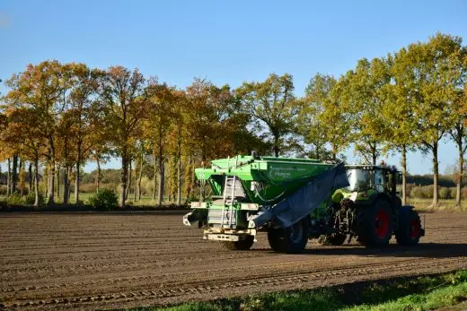Traktor rozšiřuje hnojivo na poli v podzimním krajině.