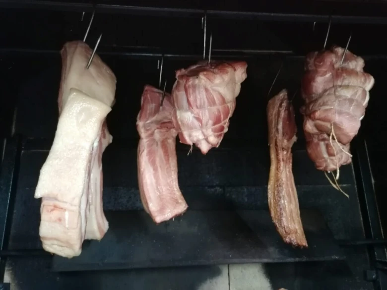 Kusy krkovice visí na háčcích v kuřáku pro uzení.