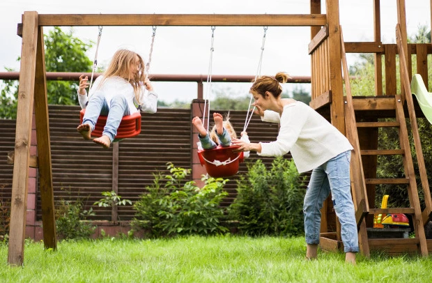 Woman pushing kids on swings