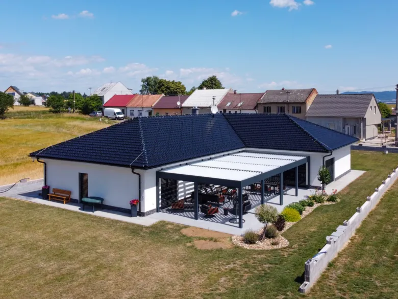 Moderní pergola s nábytkem na zahradě domu.