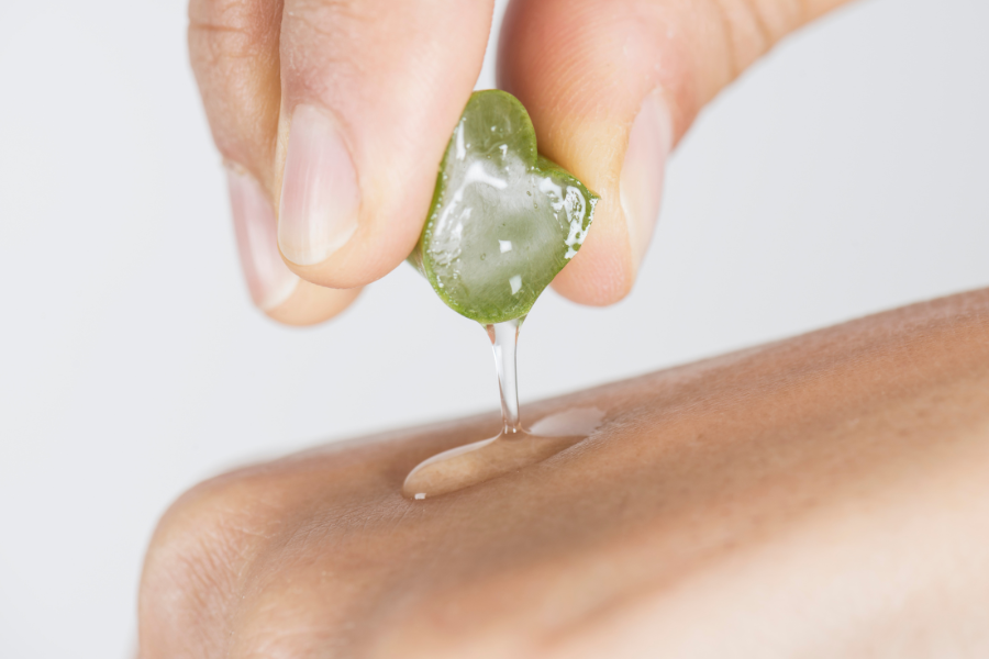 Ruce stlačují čerstvý gel z Aloe Vera na kůži.