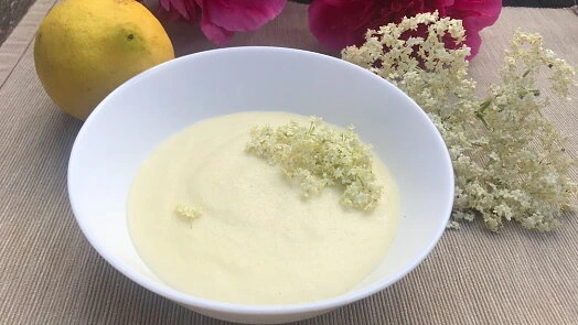 Mísa s bezovým sirupem ozdobená květy bezu vedle citronu.
