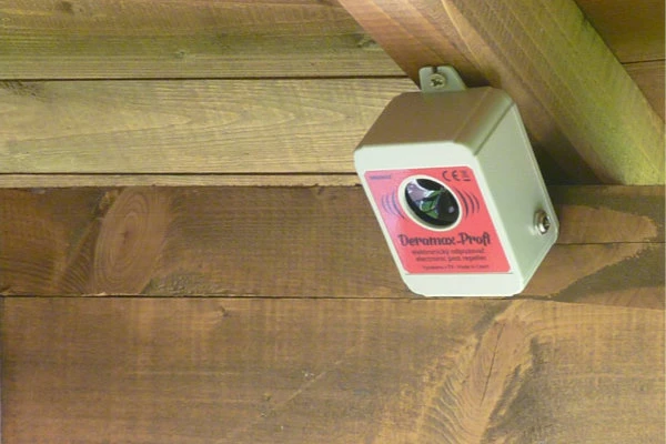 Elektronický odpuzovač myší připevněný na dřevěné trámoví.