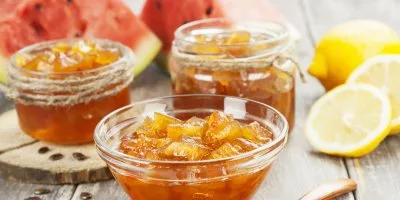 Sklenice s marmeládou z melounových slupek vedle citronů