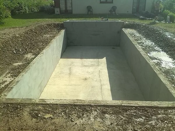 Nově vybudované betonové jezírko v zahradním pozadí.