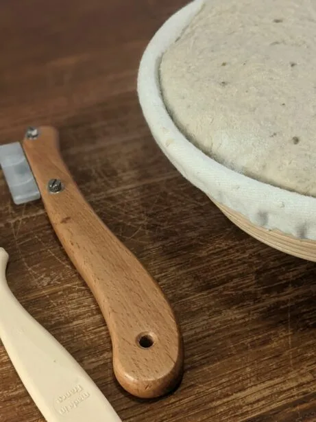 Nástroje na tvarování chleba a kynutý kvásek v misce.