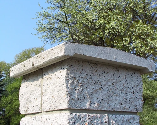 Detail betonu plotovky s ochranným krytem na vrcholu.