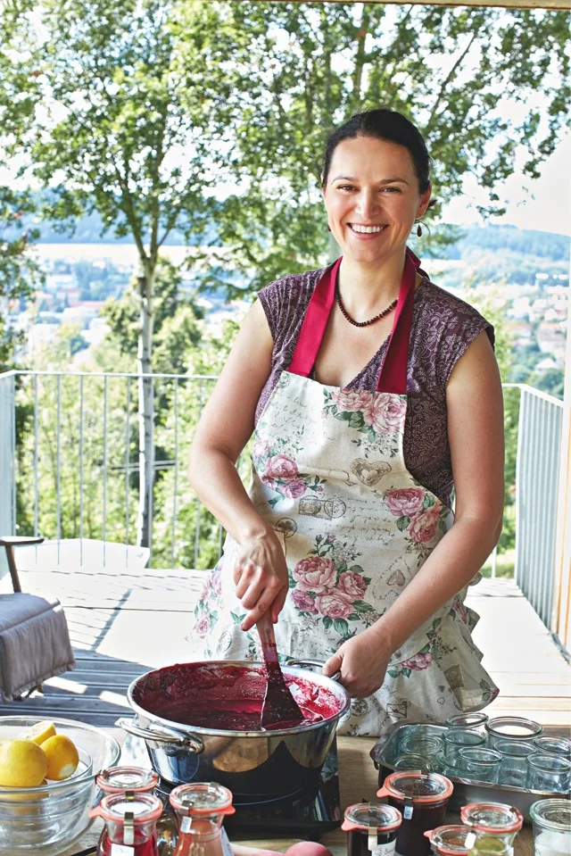 Žena míchá domácí višňovou marmeládu v hrnci na venkovní terase.