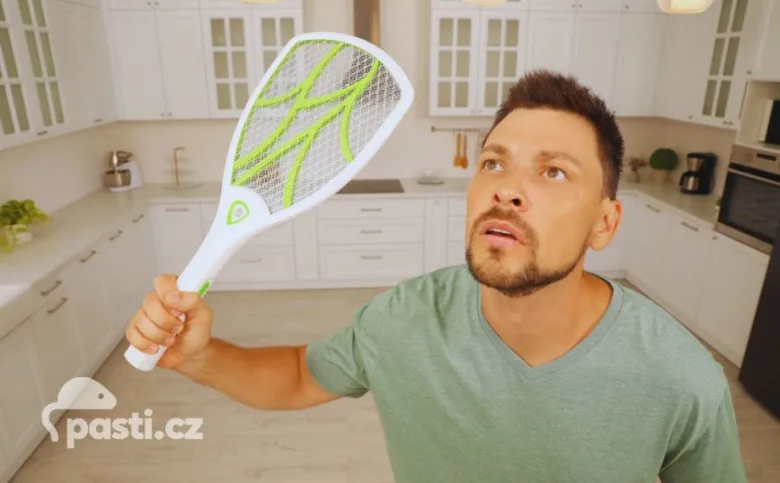 Muž drží elektrický zabíječ much v kuchyni.