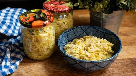 Kysané zelí v sklenicích a mísce na stolu.