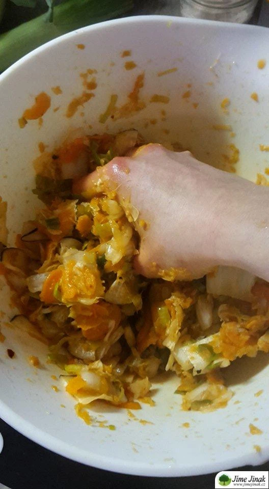 Ruka míchá nakrájenou zelí s kořením v misce při přípravě kimbap.