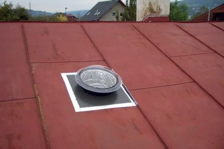 Kruhový světlovod nainstalovaný v červené střechě domu.