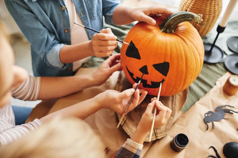 Lidé malují tvář na dýni pro halloween.